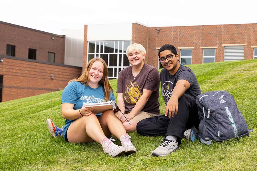 photo of three students sitting on the campus lawn
